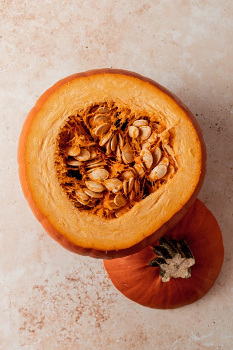 Pumpkin with the top removed, revealing its interior filled with seeds and pulp.