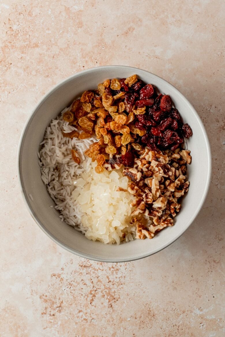 Rice, dried fruits, walnuts and sauteed onions in a bowl.