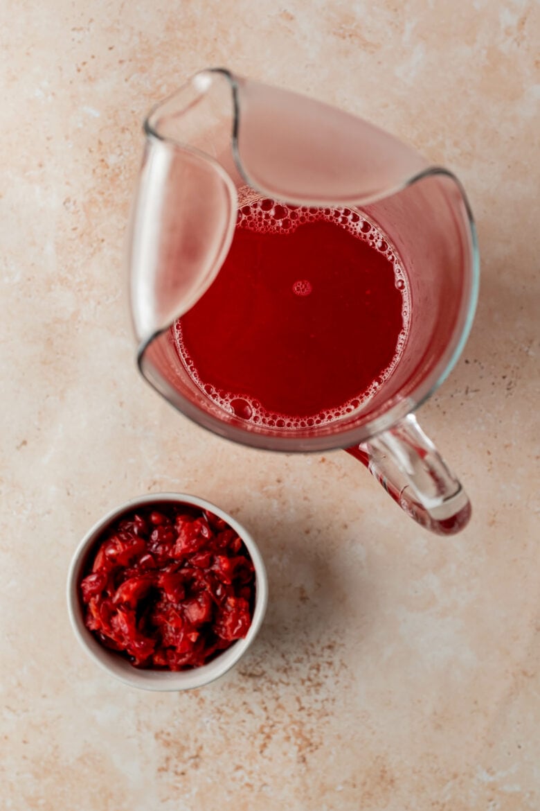 Strained cranberry juice in a pitcher with leftover cranberry pulp.