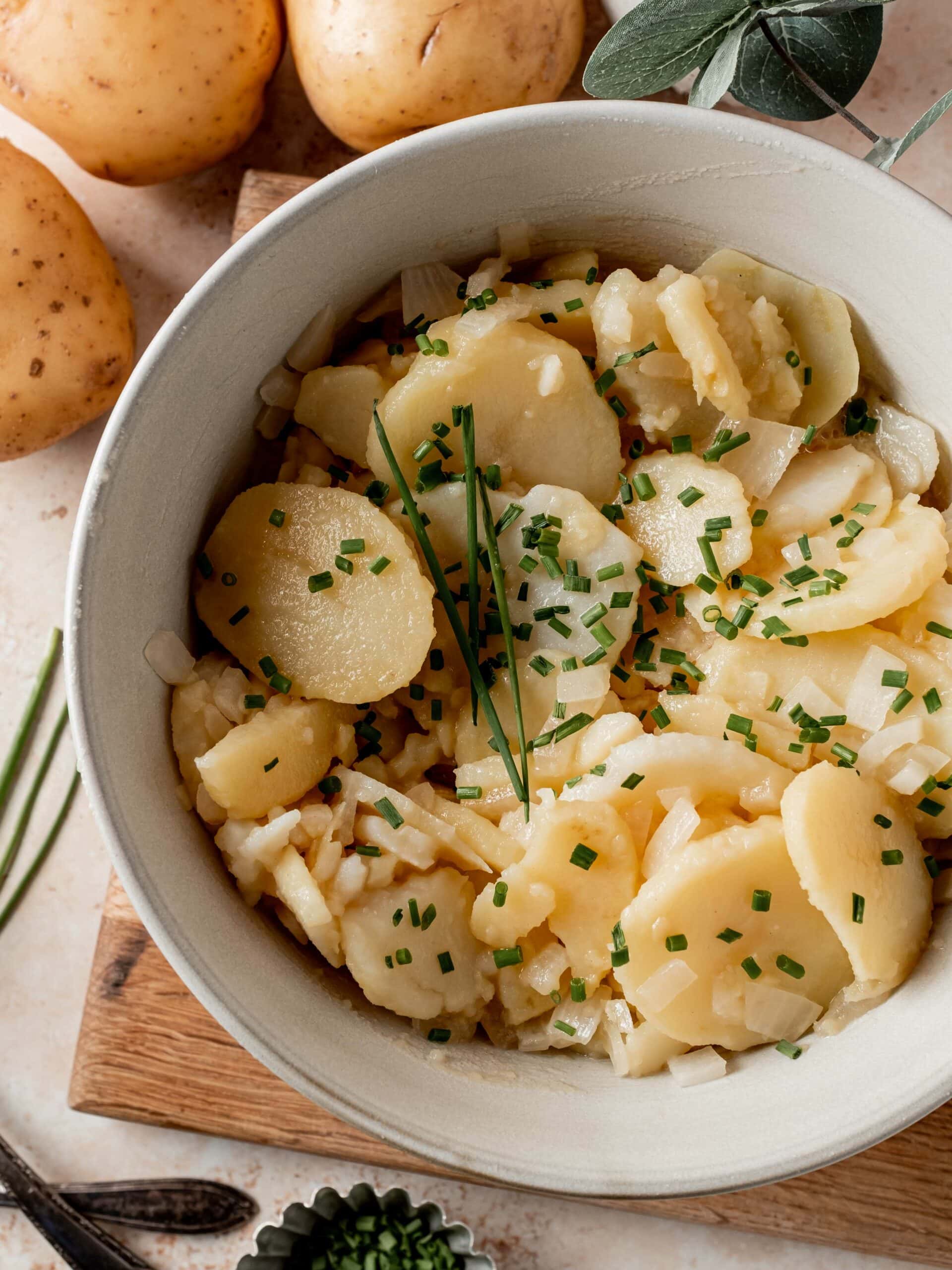 Potato salad in serving bowl with chopped chives.