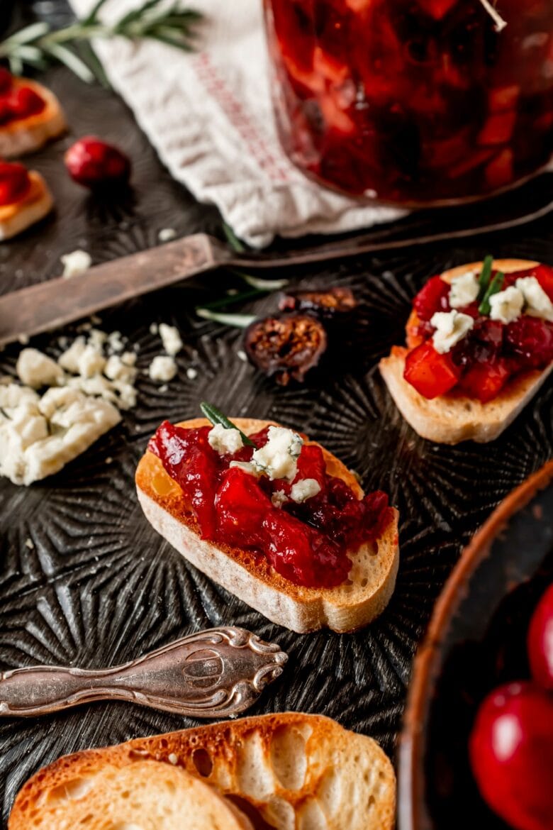Cranberry chutney on crostini with blue cheese and garnished with rosemary.