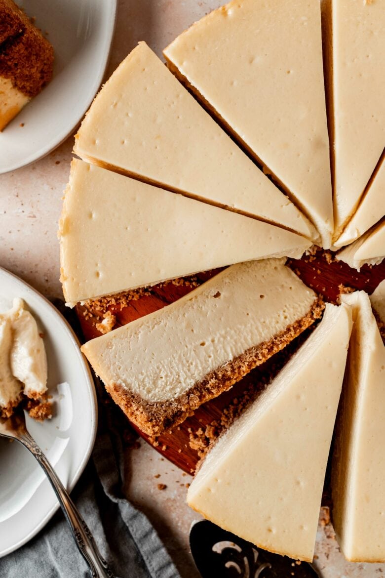 Overhead view of sliced cheesecake with one piece on its side to display creamy texture.