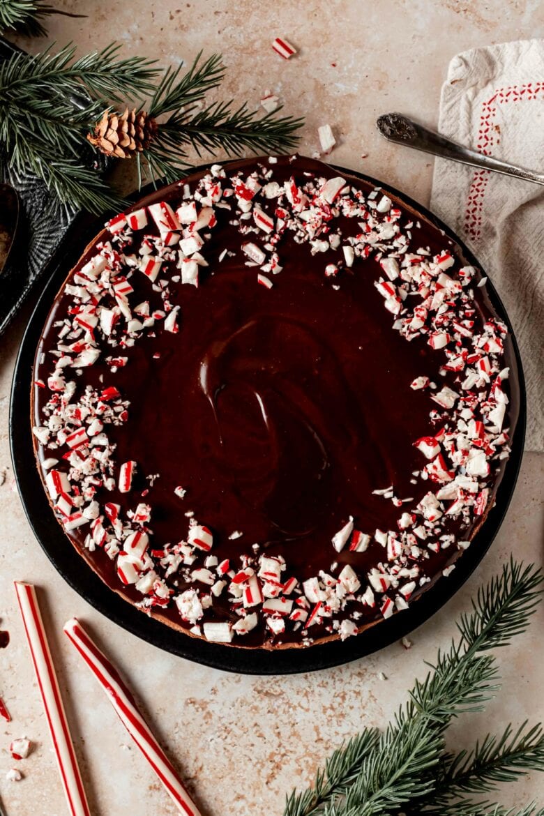 Overhead view of cheesecake with ganache and crushed candy cane garnish.