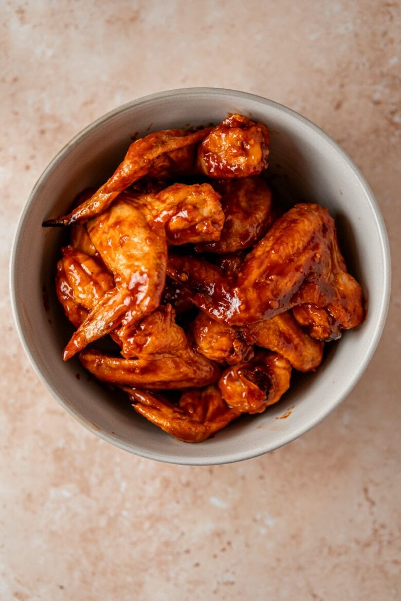 Baked wings in a bowl tossed with Gochujang sauce.