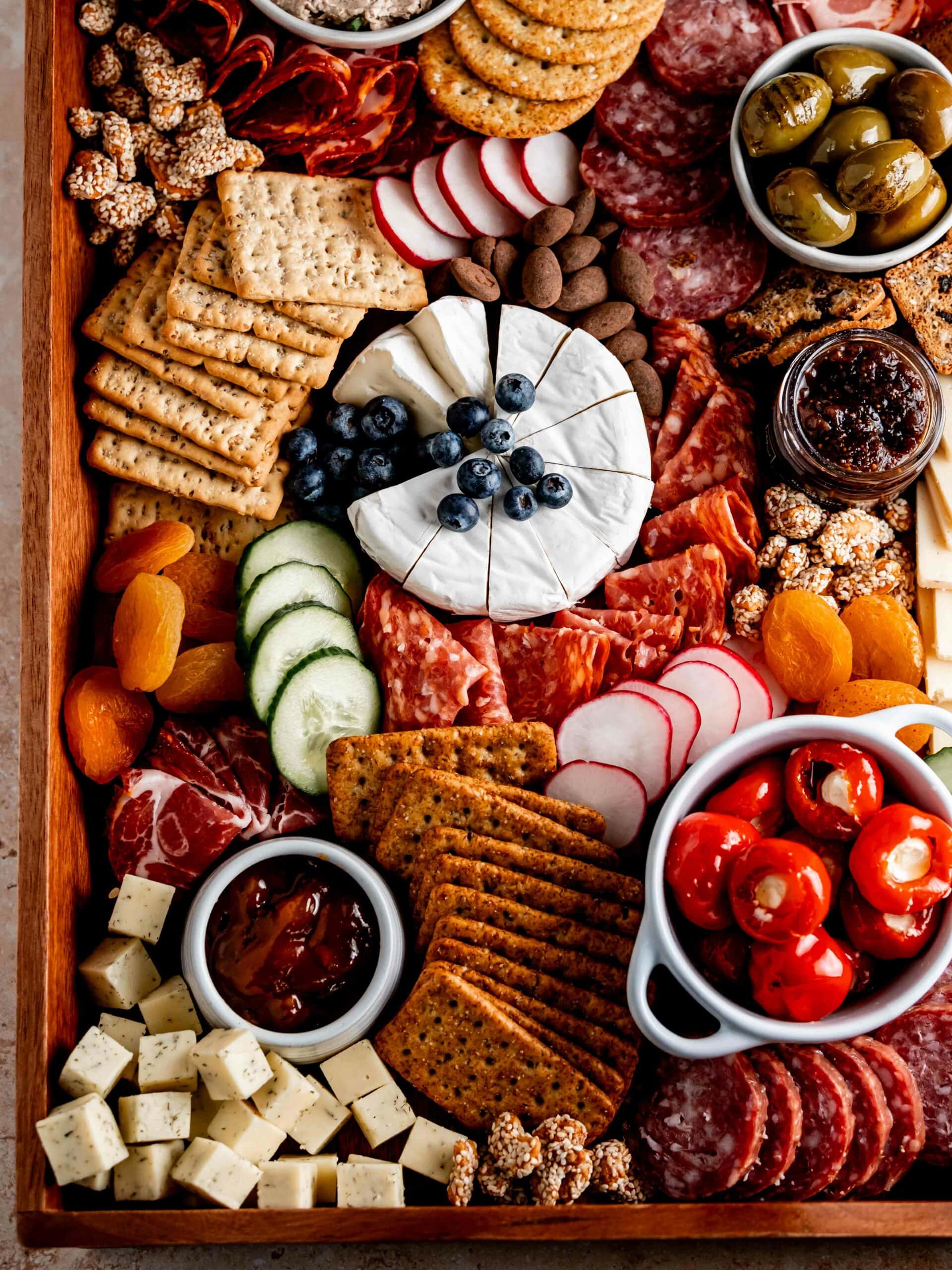 Homemade charcuterie board with cured meats, creamy cheeses, crackers, olives, jams, candied nuts and more!