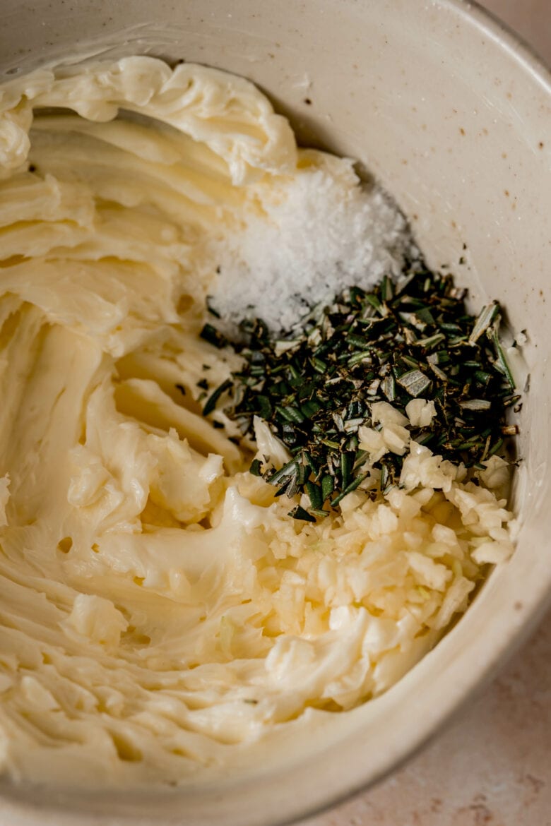 Close up of minced garlic and chopped rosemary with butter.