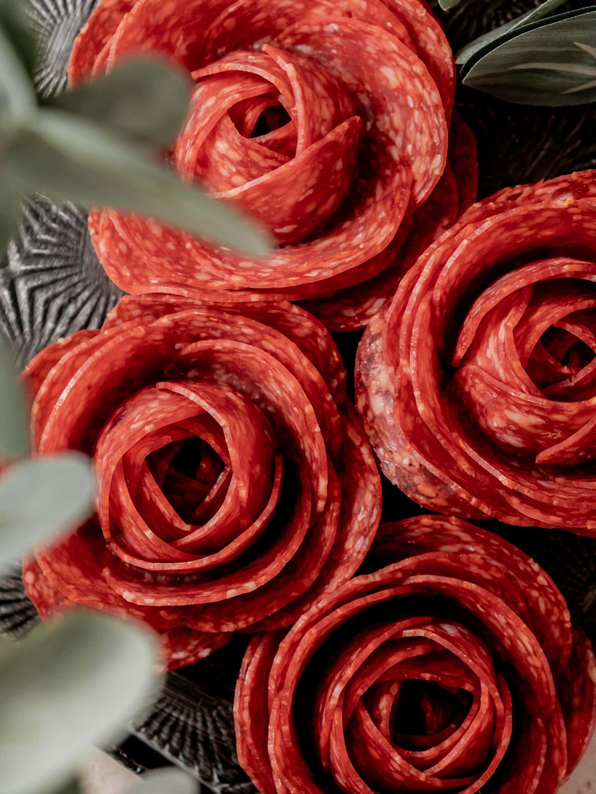 Four salami roses on a metal tray.