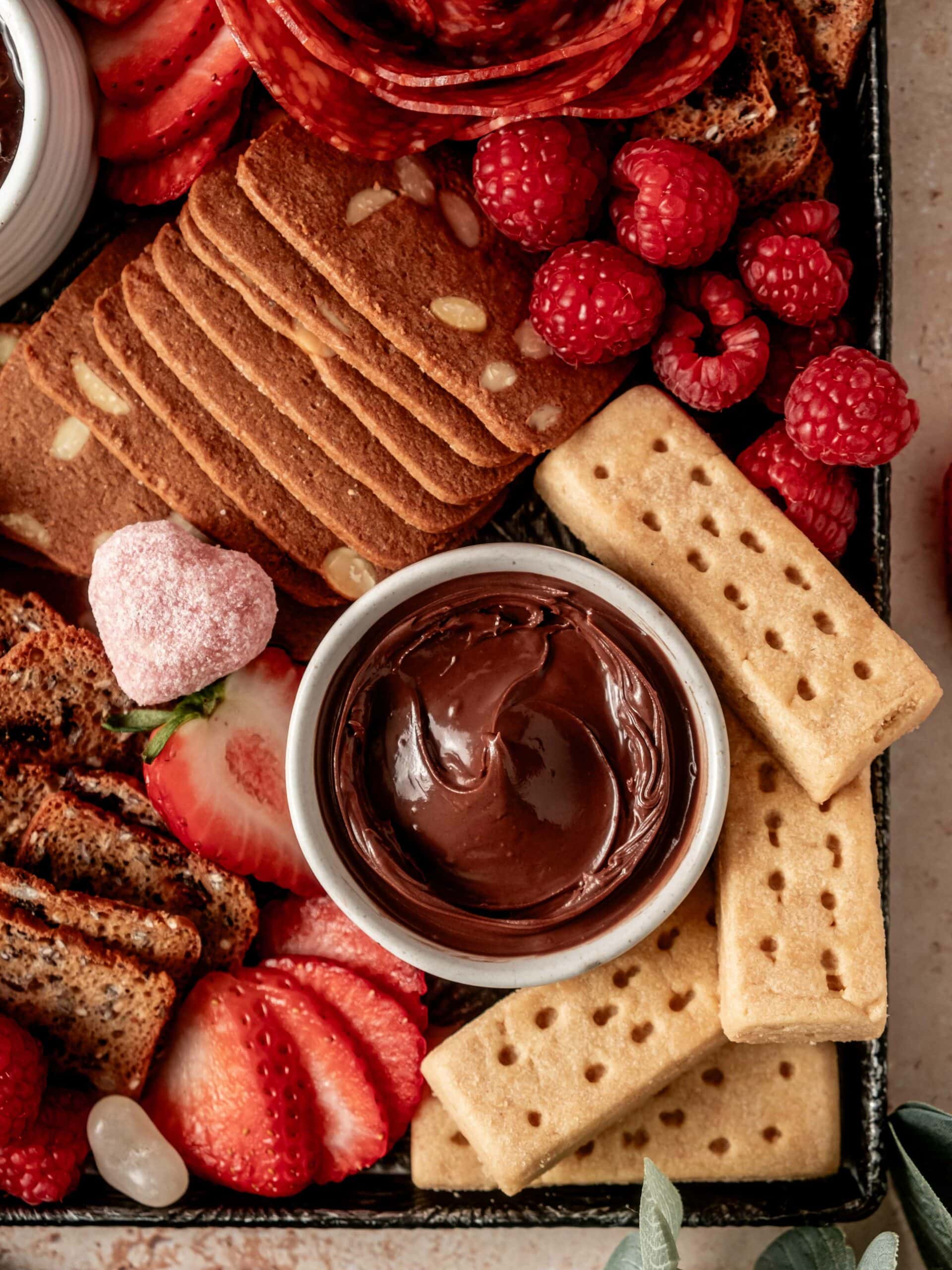 Valentine's charcuterie board featuring an assortment of sweet cookies and snacks and a few savory treats.