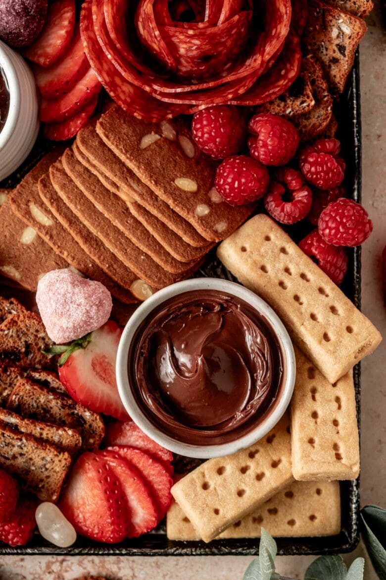 Valentine's charcuterie board featuring an assortment of sweet cookies and snacks and a few savory treats.