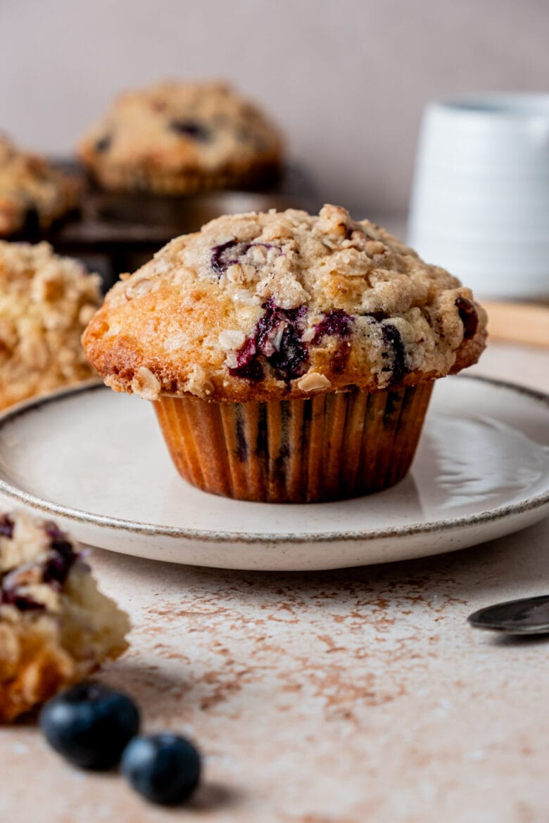 Large blueberry muffin on a plate with crispy streusel topping.