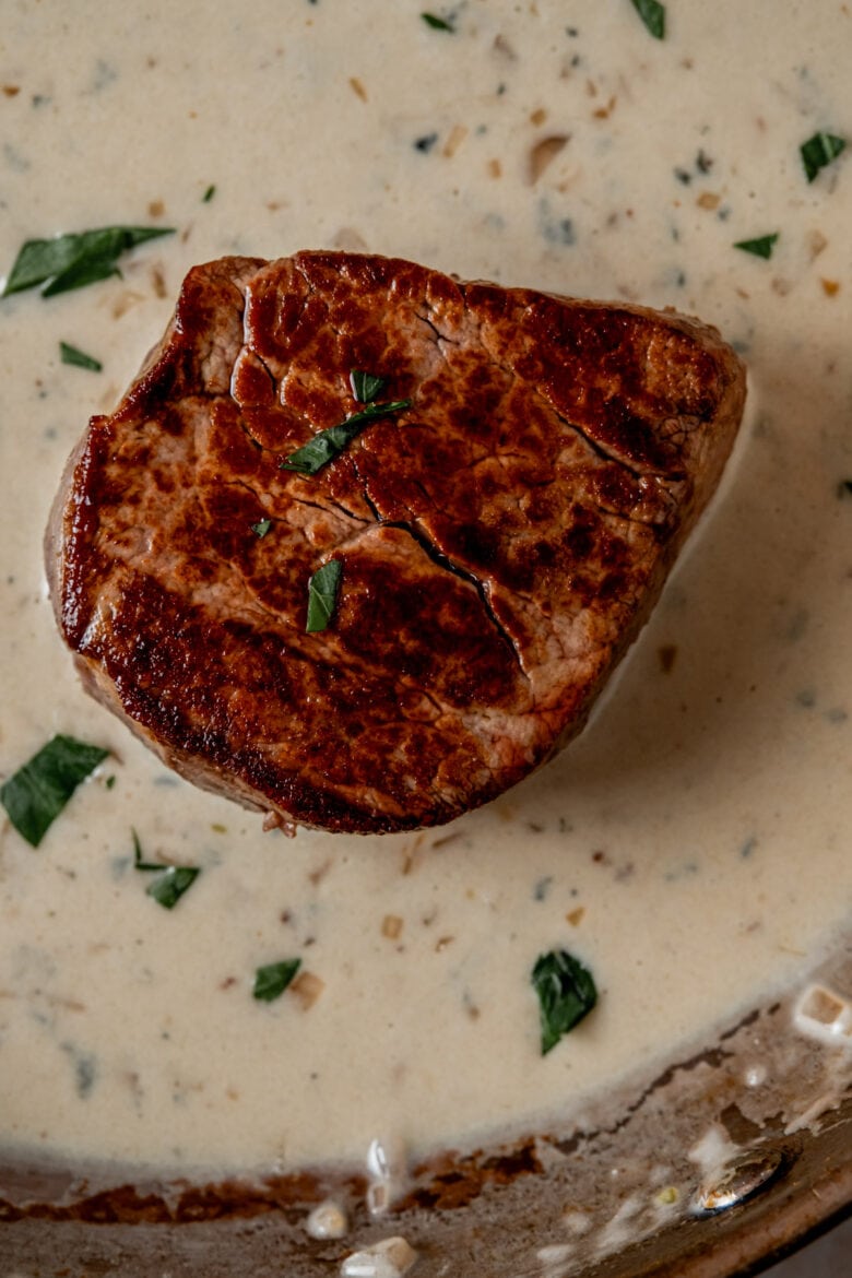 Seared whole filet mignon steak in blue cheese sauce.