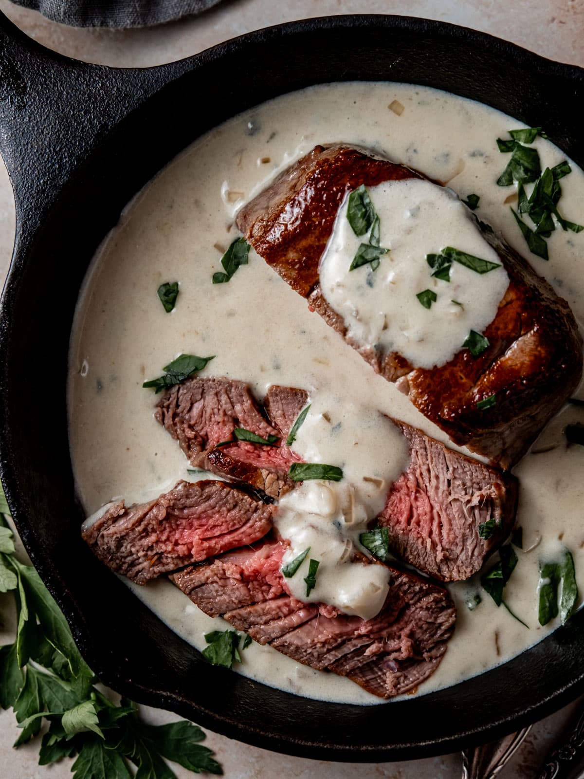 Tender filet mignon slices in small cast iron skillet, smothered in savory blue cheese sauce and topped with parsley