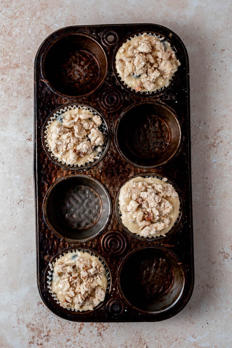 Muffin batter in tin topped with streusel.