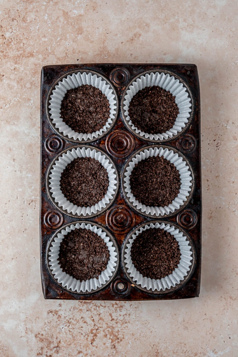 Oreo cheesecake crusts in cupcake liners in muffin tin.