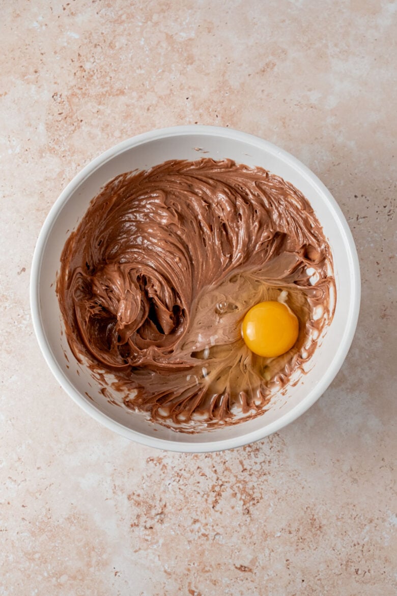 Adding eggs to Nutella cheesecake batter.