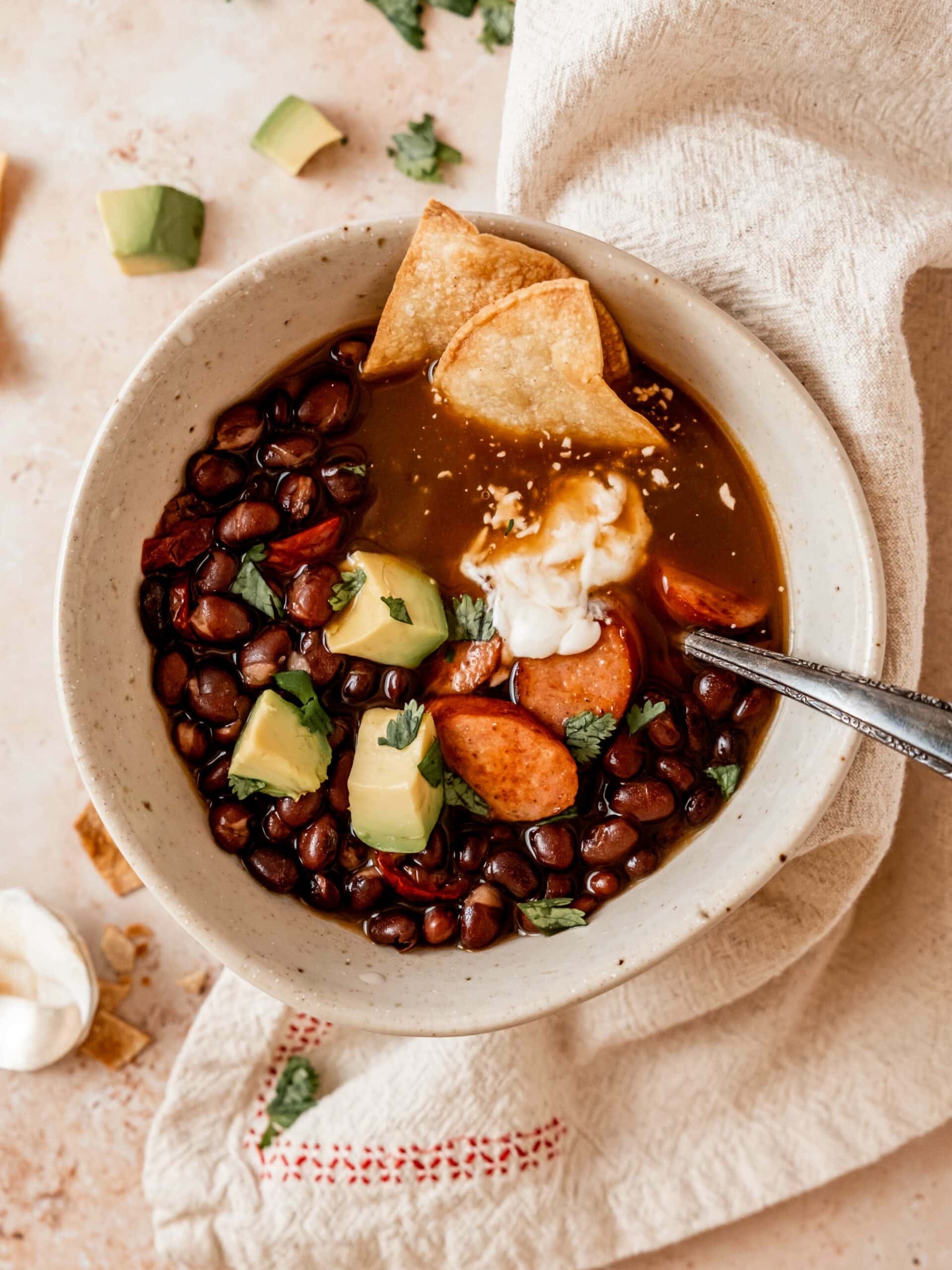 Spicy black bean soup with sausages, avocado and tortilla chips.