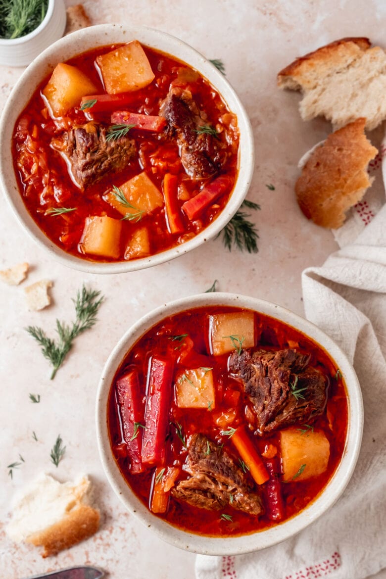 Two big bowls of borscht with beets, potatoes, carrots and tender chunks of beef.