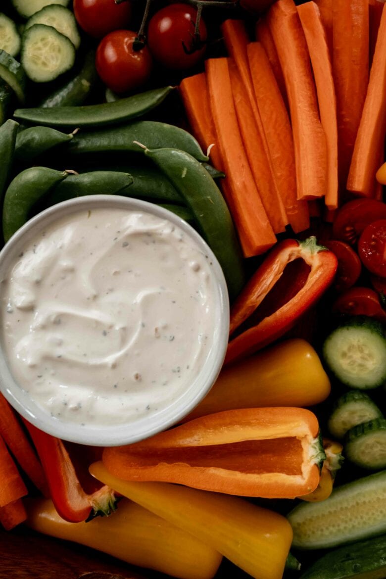 Close up of creamy dip in small dish on vegetable tray.