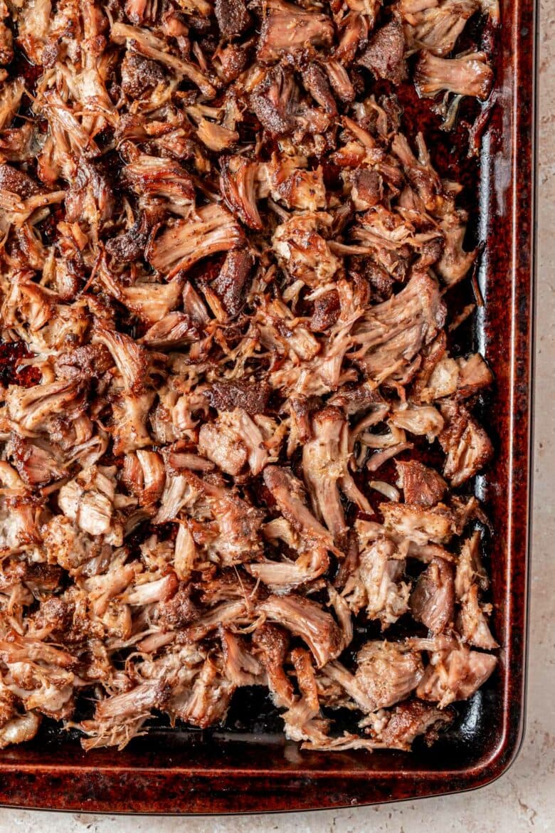 Crispy pieces of shredded carnitas on a pan after broiling.
