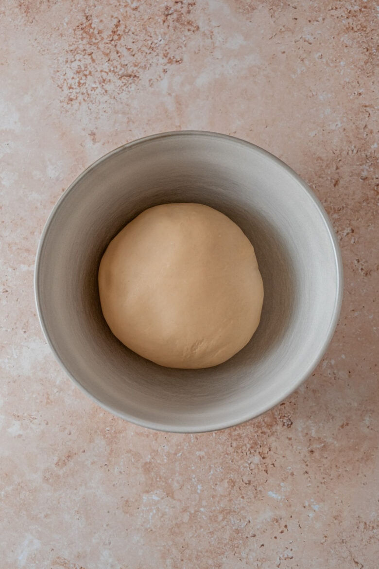 Smooth and elastic ball of dough in mixing bowl after kneading and resting.