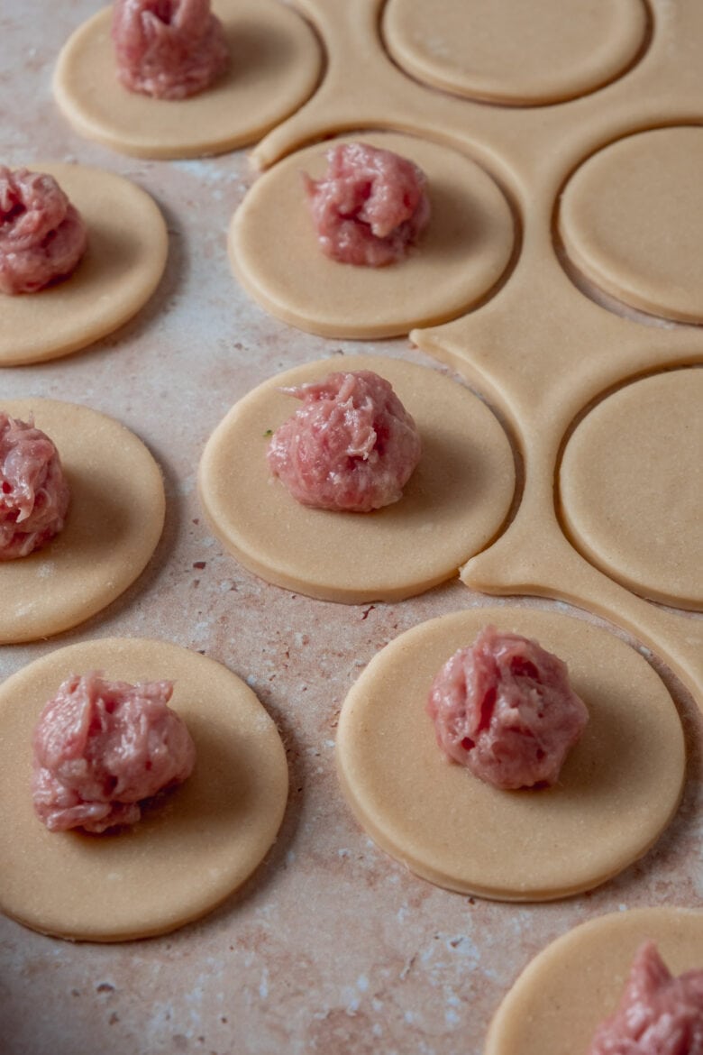 Pelmeni dough rounds with meat filling on top.