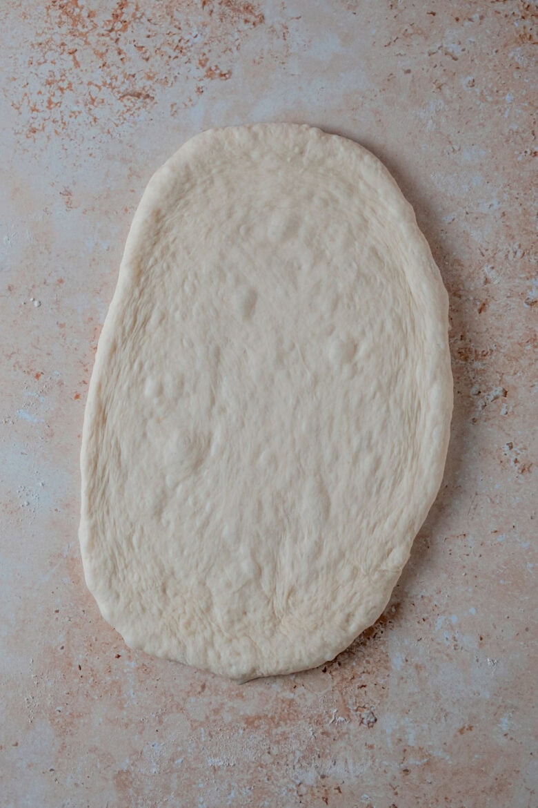 Rolling out the dough into an oval.