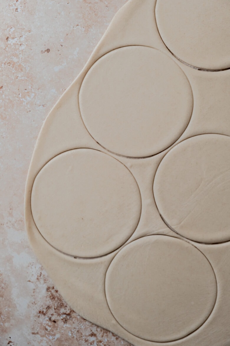 Rolled out dough with circles cut out.