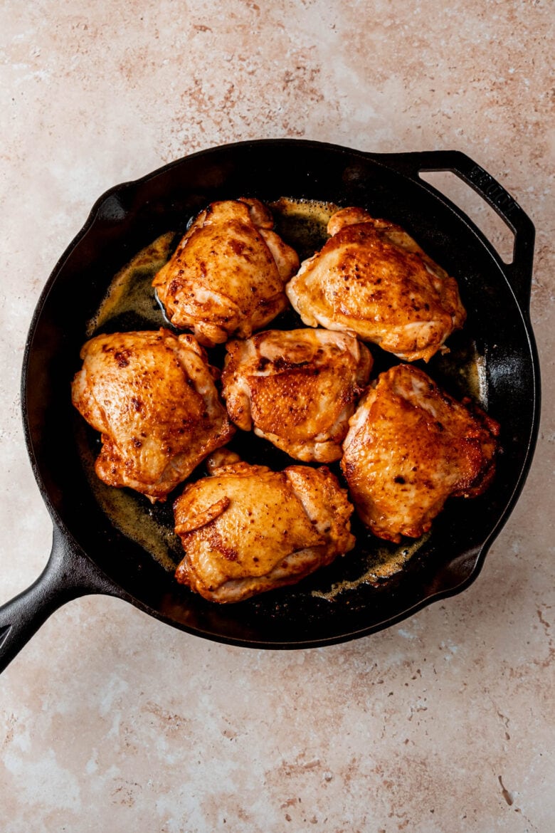 Seared chicken thighs in cast iron skillet.