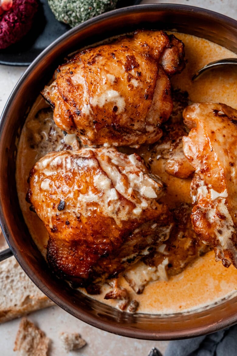 Golden brown chicken thighs with garlic sauce drizzled over the top.