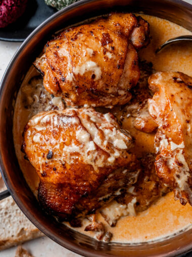 Crispy chicken thighs in dish with creamy garlic sauce.