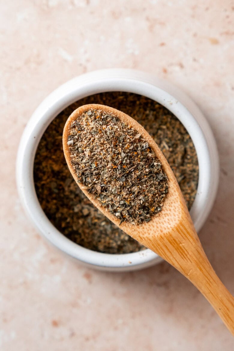 Wooden spoon with spice blend over small dish with spices.
