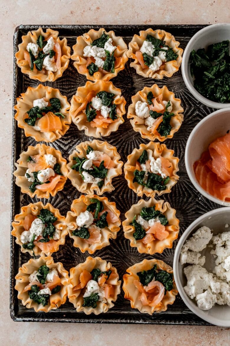 Small dishes containing blanched spinach, smoked salmon and crumbled goat cheese along with phyllo cups for filling.