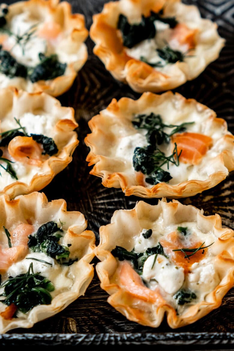 Golden brown phyllo cups filled with smoked salmon, goat cheese and spinach and garnished with dill.