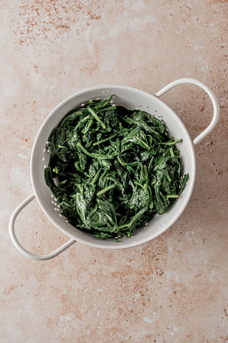 Blanched spinach in a colander.