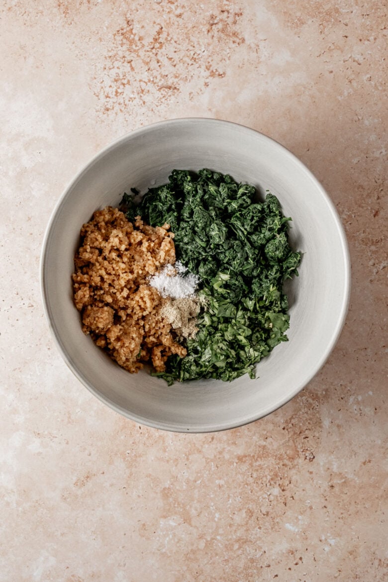 Chopped spinach, coriander, walnut paste and spices in a mixing bowl.