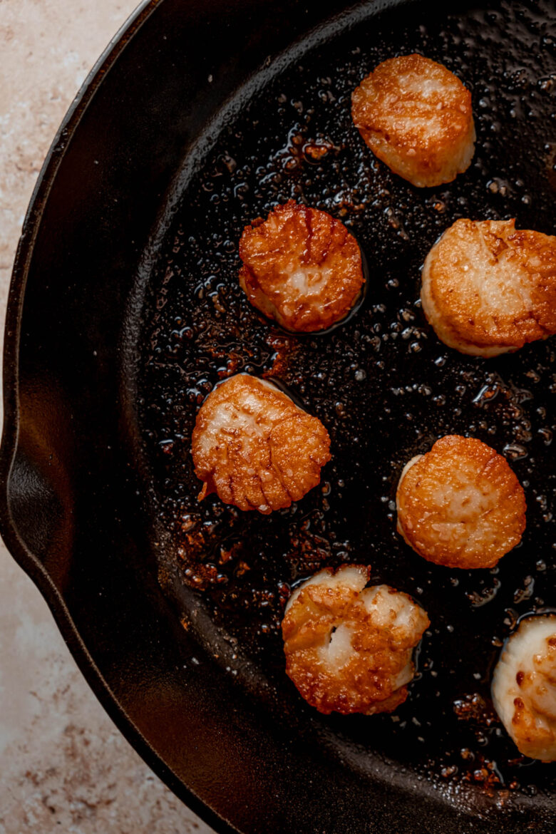 Seared scallops in cast iron skillet.