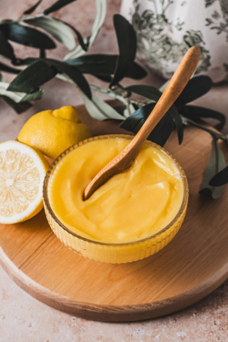 Smooth lemon curd in a bowl with a spoon.