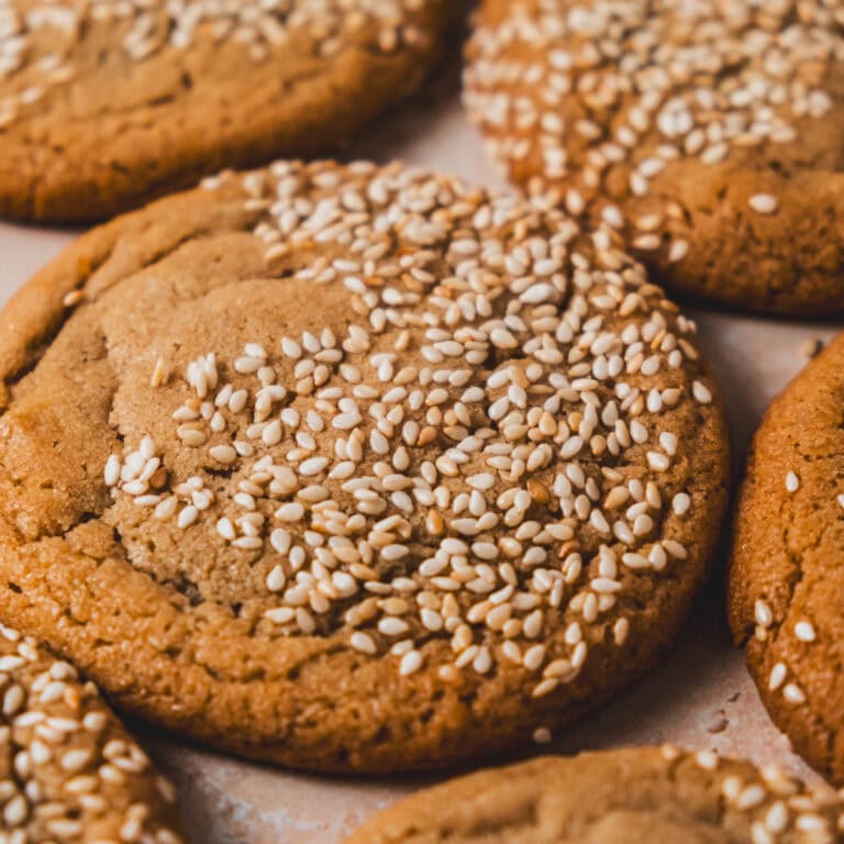 Close up of golden cookie covered in toasted sesame seeds.